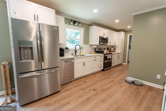 kitchen featuring backsplash, crown molding, light countertops, stainless steel appliances, and a sink