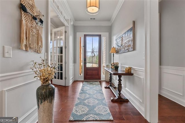 entrance foyer with dark wood finished floors, a wainscoted wall, crown molding, and visible vents