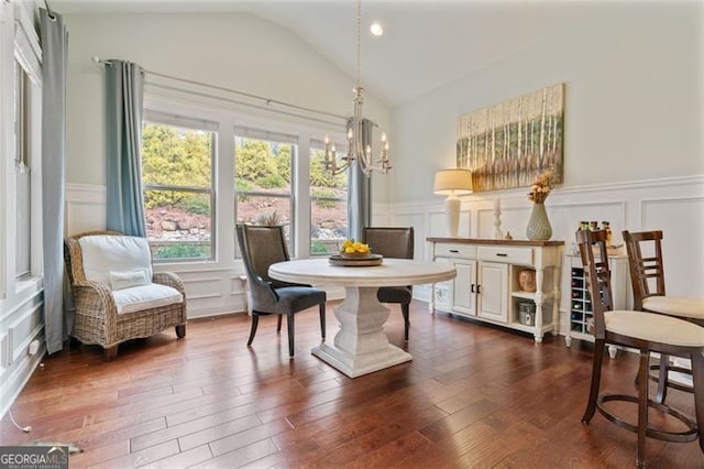 dining room with a chandelier, a decorative wall, vaulted ceiling, and dark wood-style flooring