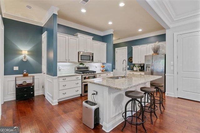 kitchen with a kitchen island with sink, stainless steel appliances, dark wood-type flooring, and a sink