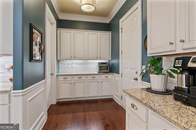 kitchen with white cabinets, crown molding, decorative backsplash, light stone countertops, and dark wood-style flooring