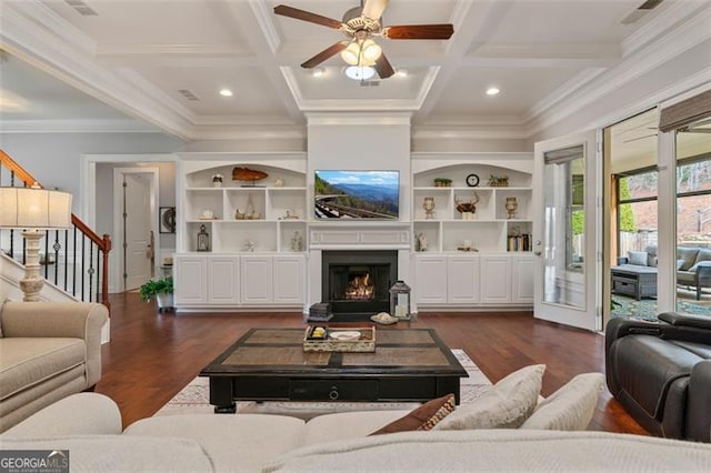 living room featuring dark wood-type flooring, beamed ceiling, stairway, a warm lit fireplace, and coffered ceiling