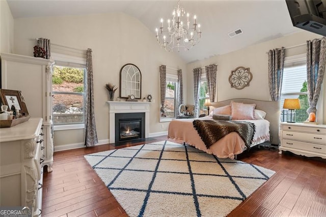 bedroom with visible vents, a glass covered fireplace, dark wood-style floors, baseboards, and lofted ceiling