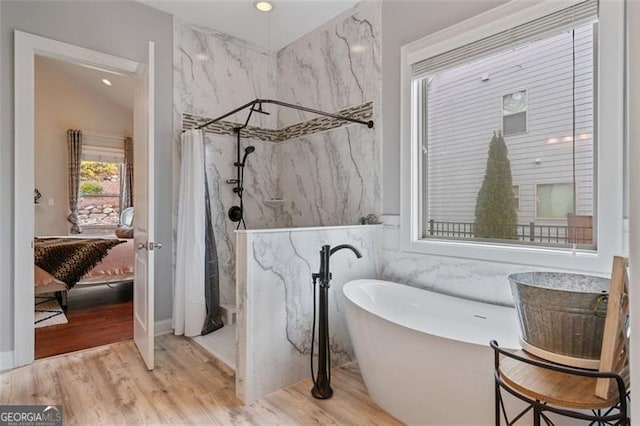 bathroom featuring a marble finish shower, a soaking tub, ensuite bathroom, and wood finished floors