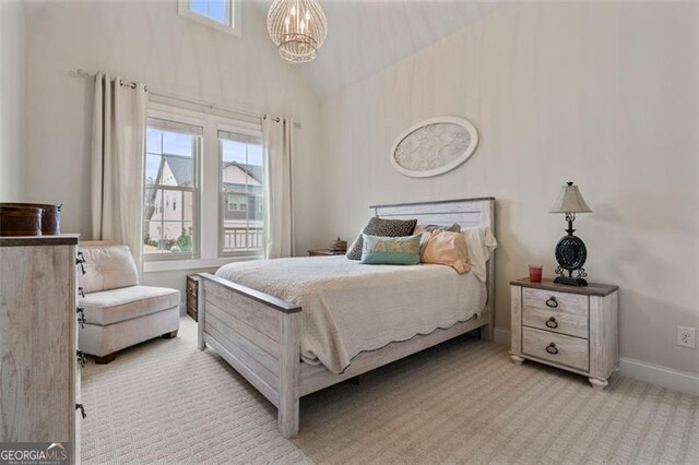 bedroom featuring a notable chandelier, light colored carpet, baseboards, and high vaulted ceiling