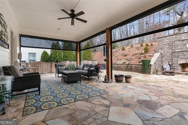 view of patio / terrace featuring an outdoor living space with a fireplace, a ceiling fan, and fence