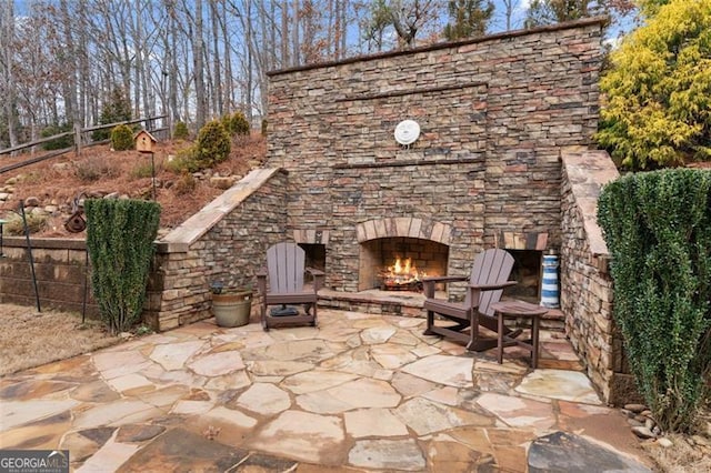 view of patio with fence and an outdoor stone fireplace