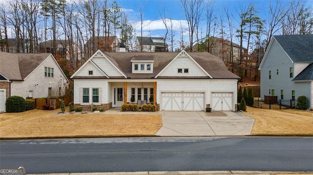 view of front of house with an attached garage, concrete driveway, and fence