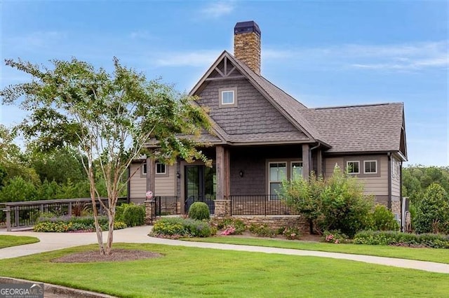 craftsman-style home with a porch, a chimney, a front lawn, and a shingled roof