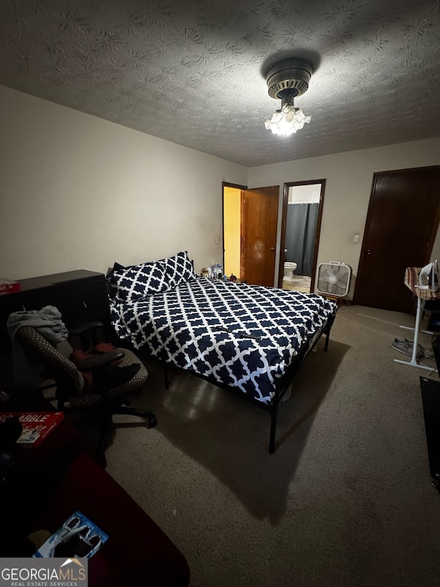 carpeted bedroom with a textured ceiling and ensuite bath