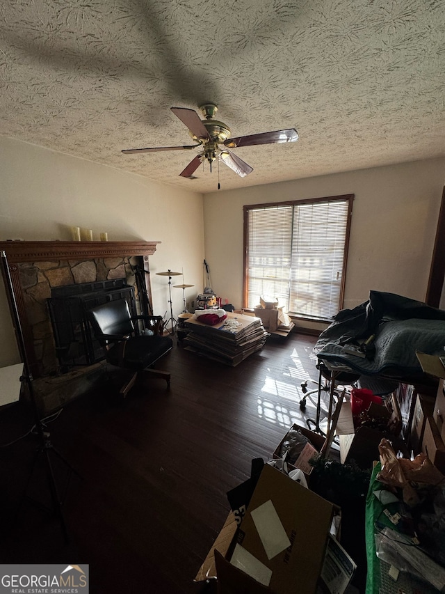 interior space with a ceiling fan, a textured ceiling, wood finished floors, and a fireplace