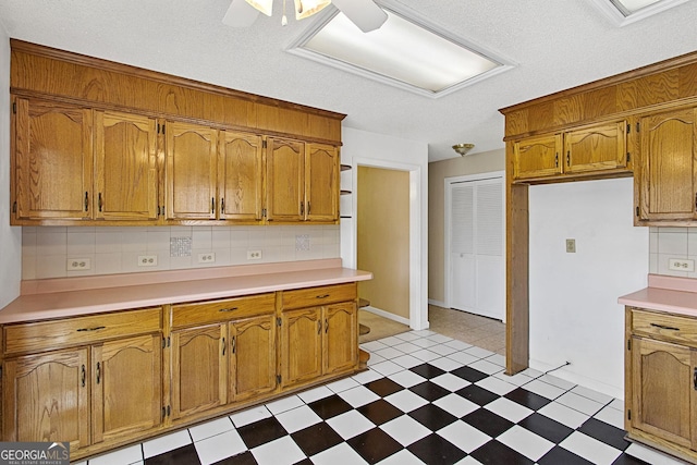 kitchen with light floors, brown cabinets, ceiling fan, light countertops, and tasteful backsplash