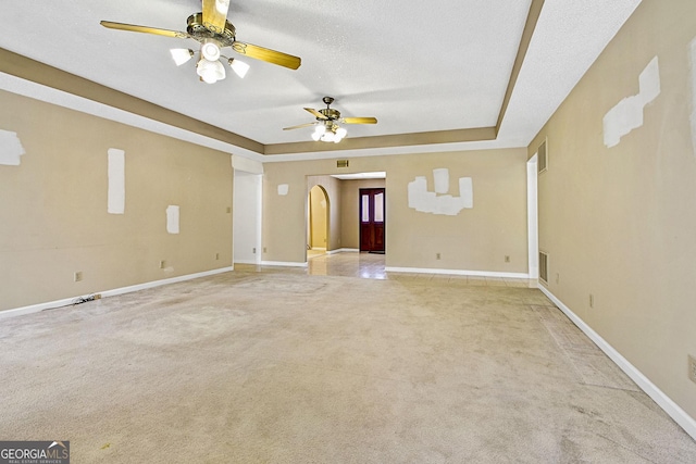 carpeted spare room featuring baseboards, visible vents, a textured ceiling, and a tray ceiling