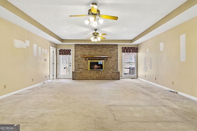 unfurnished living room featuring a brick fireplace, a textured ceiling, baseboards, and carpet floors