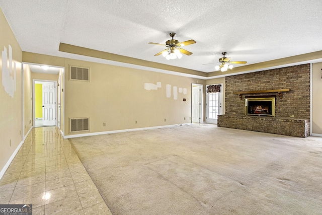 unfurnished living room featuring visible vents, a raised ceiling, light carpet, and a fireplace