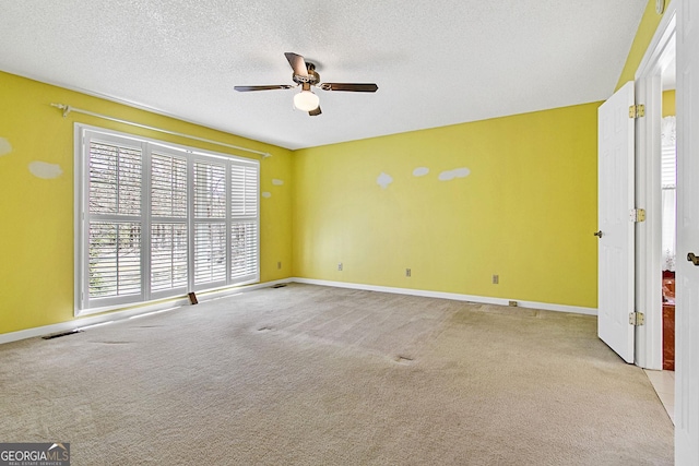 carpeted empty room with visible vents, baseboards, a textured ceiling, and a ceiling fan