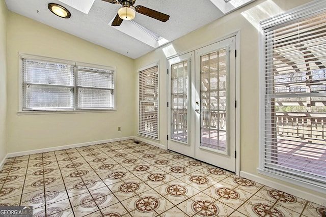 doorway to outside with baseboards, ceiling fan, vaulted ceiling with skylight, light tile patterned flooring, and a textured ceiling