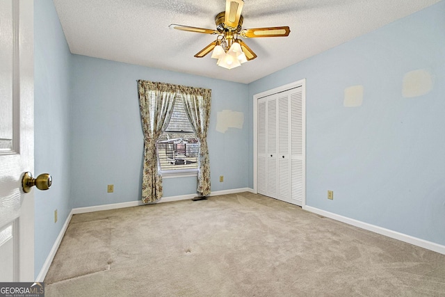 unfurnished bedroom featuring a ceiling fan, a textured ceiling, a closet, carpet flooring, and baseboards