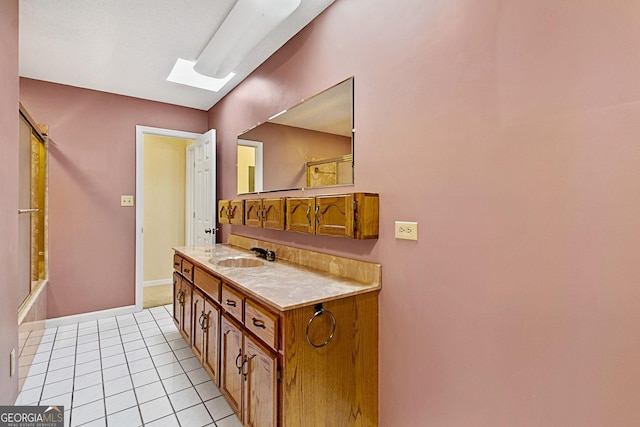 bathroom featuring baseboards, a skylight, bathtub / shower combination, tile patterned floors, and vanity