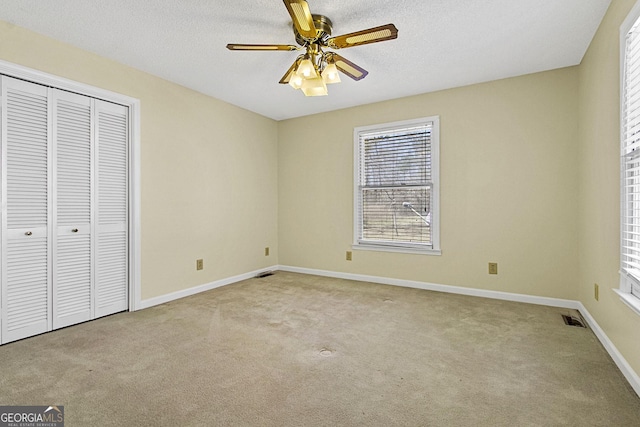 unfurnished bedroom with visible vents, a textured ceiling, a closet, carpet flooring, and baseboards