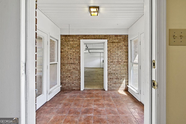 hallway with tile patterned floors and brick wall