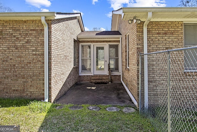 doorway to property featuring brick siding and a patio area