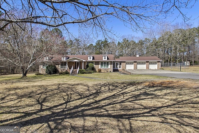 view of front of house with a front lawn, an attached garage, fence, and driveway