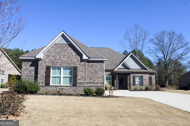 craftsman-style home featuring brick siding, a front yard, and a shingled roof