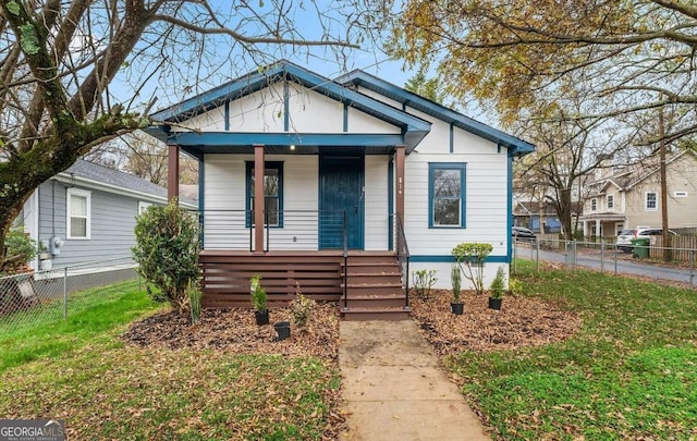 bungalow featuring covered porch, a front yard, and fence