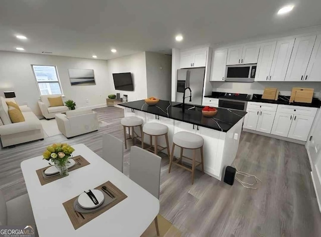 kitchen featuring dark countertops, open floor plan, stainless steel appliances, and a sink