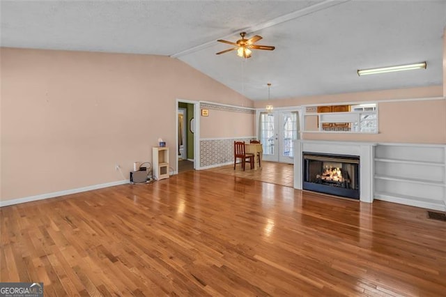 unfurnished living room featuring a ceiling fan, wood finished floors, baseboards, a multi sided fireplace, and vaulted ceiling