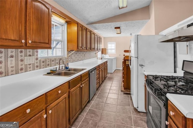 kitchen with a sink, vaulted ceiling, under cabinet range hood, a textured ceiling, and appliances with stainless steel finishes