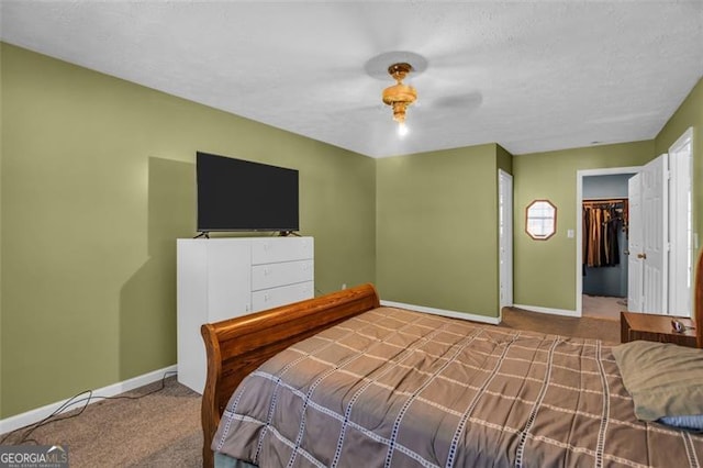 carpeted bedroom with ceiling fan, a textured ceiling, and baseboards