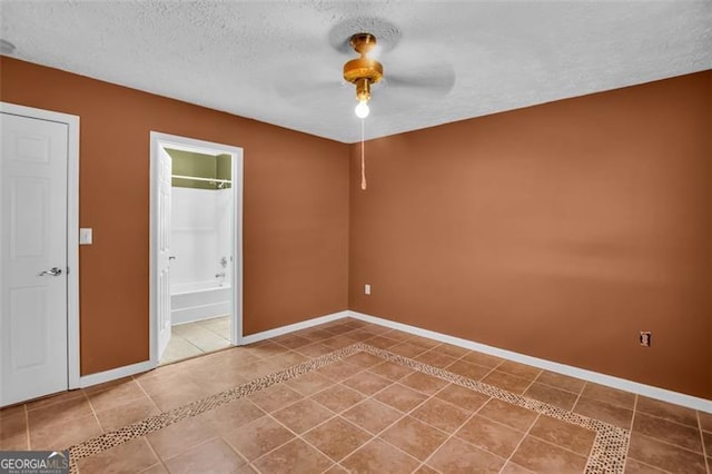 unfurnished bedroom featuring tile patterned flooring, connected bathroom, baseboards, ceiling fan, and a textured ceiling