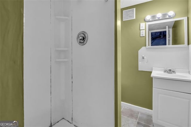 bathroom featuring visible vents, baseboards, and vanity