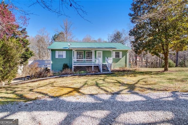 view of front of house featuring covered porch, metal roof, and a front yard