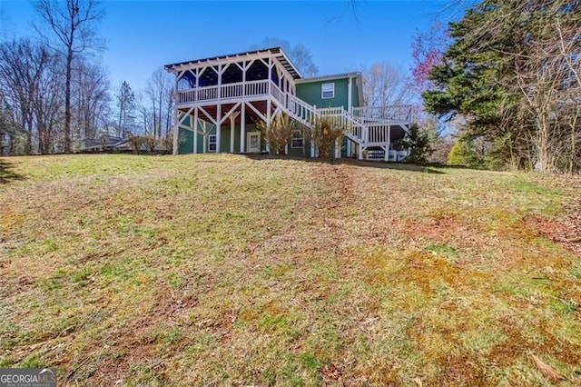 rear view of property featuring stairway, a yard, and a deck