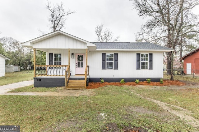 view of front of home featuring a front lawn, covered porch, and roof with shingles