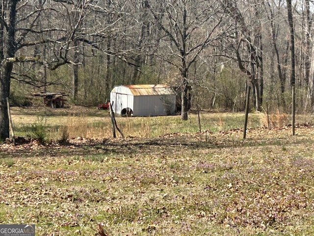 view of yard with an outbuilding, a storage shed, and a view of trees