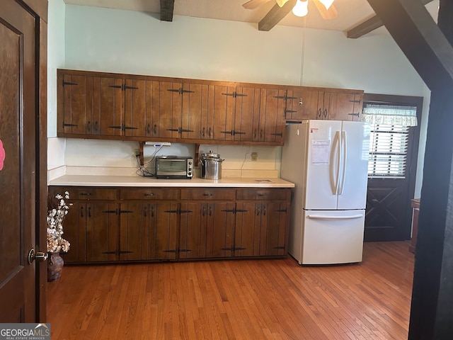 kitchen with beam ceiling, light wood-style flooring, light countertops, and freestanding refrigerator