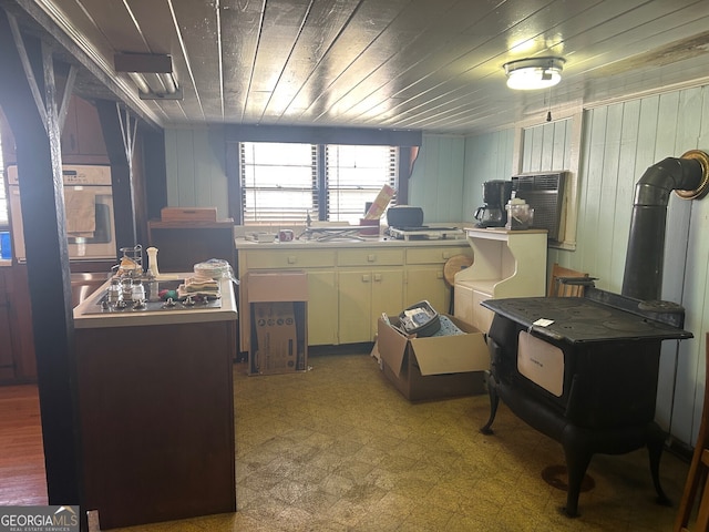 kitchen with oven, light floors, wooden ceiling, and wooden walls