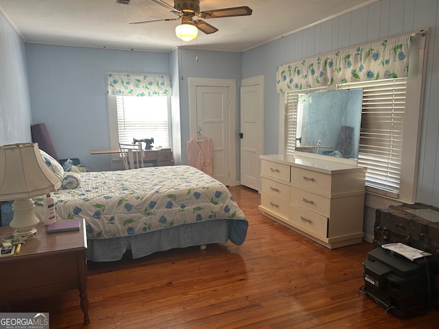 bedroom with a ceiling fan, crown molding, wood finished floors, and visible vents