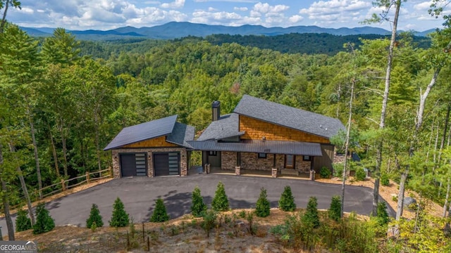 view of front of home featuring a mountain view, a wooded view, and stone siding