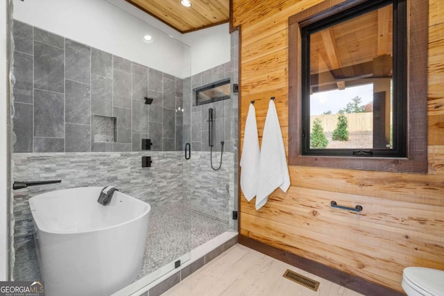 bathroom with visible vents, wooden walls, recessed lighting, a stall shower, and a freestanding tub