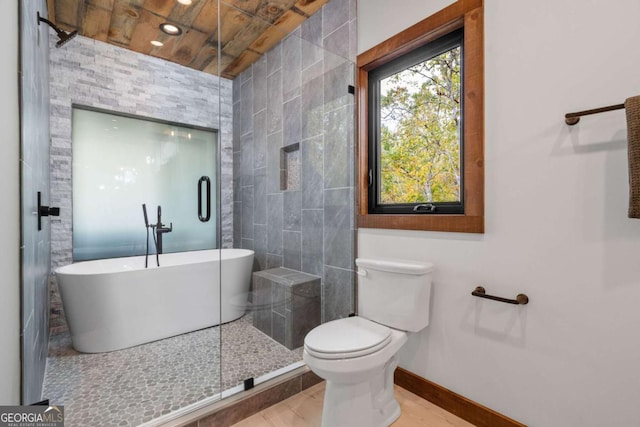 bathroom with a freestanding tub, baseboards, and toilet