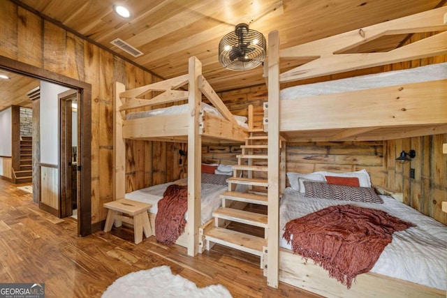 bedroom with wood ceiling, wood finished floors, visible vents, and wood walls