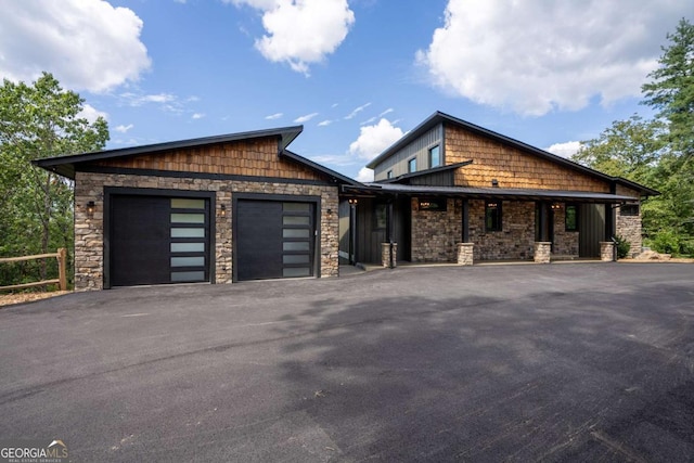 view of front of house with an attached garage, stone siding, and driveway