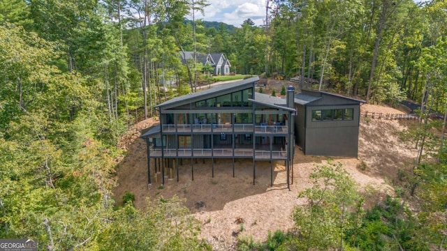 rear view of property with a deck and a forest view