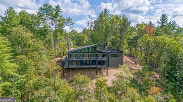 back of property with a wooden deck and a forest view