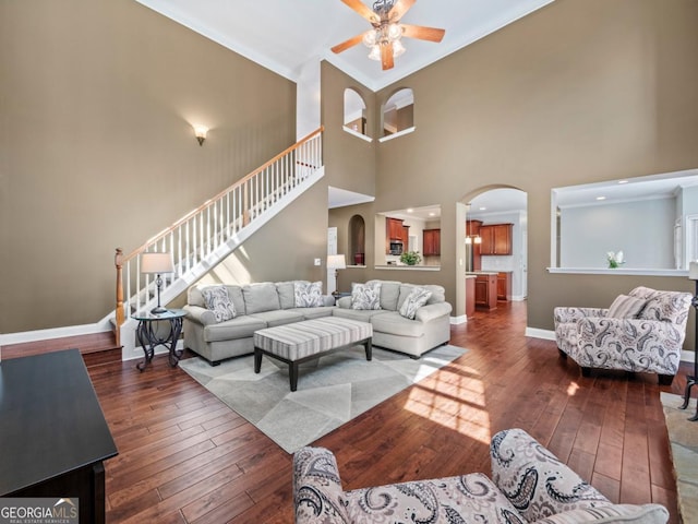 living area with baseboards, arched walkways, ceiling fan, stairs, and wood-type flooring